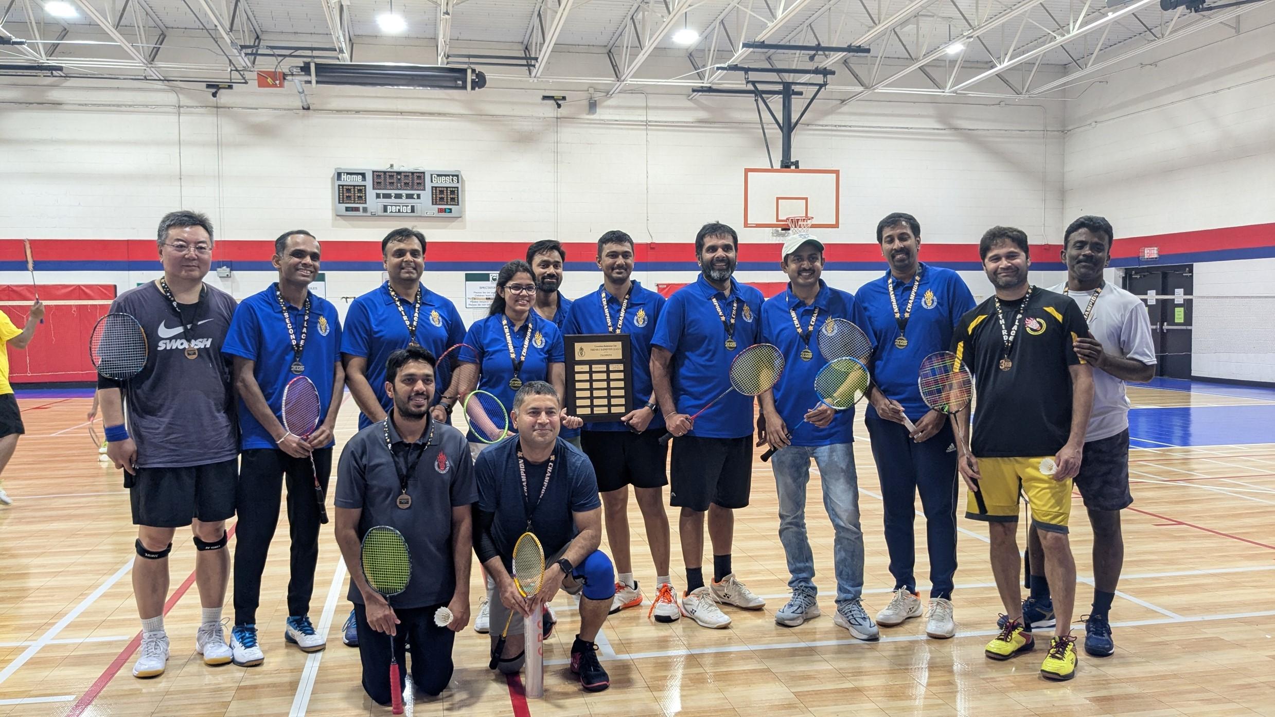 Greensboro Badminton Club players gathered on court with rackets and tournament medals